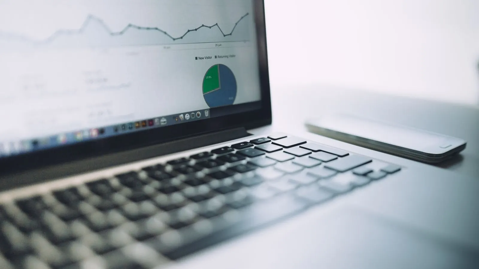 Laptop showing an analytics dashboard with line and pie charts