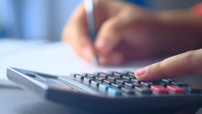 Hands using a calculator while writing down figures