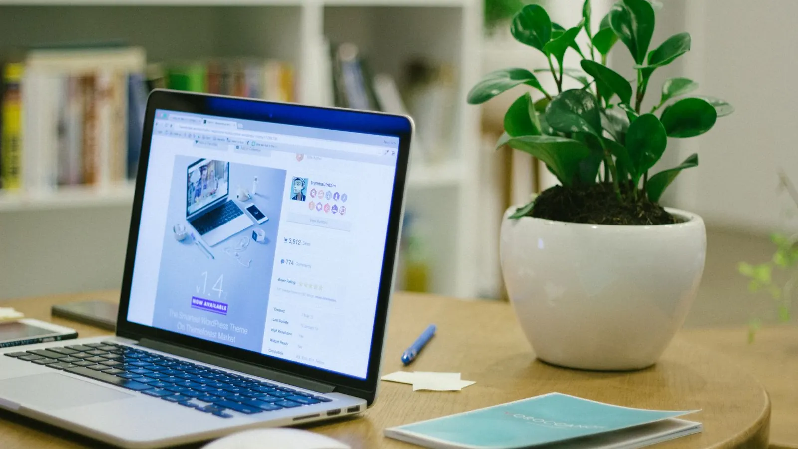 Laptop showing a business website on a desk beside a potted plant