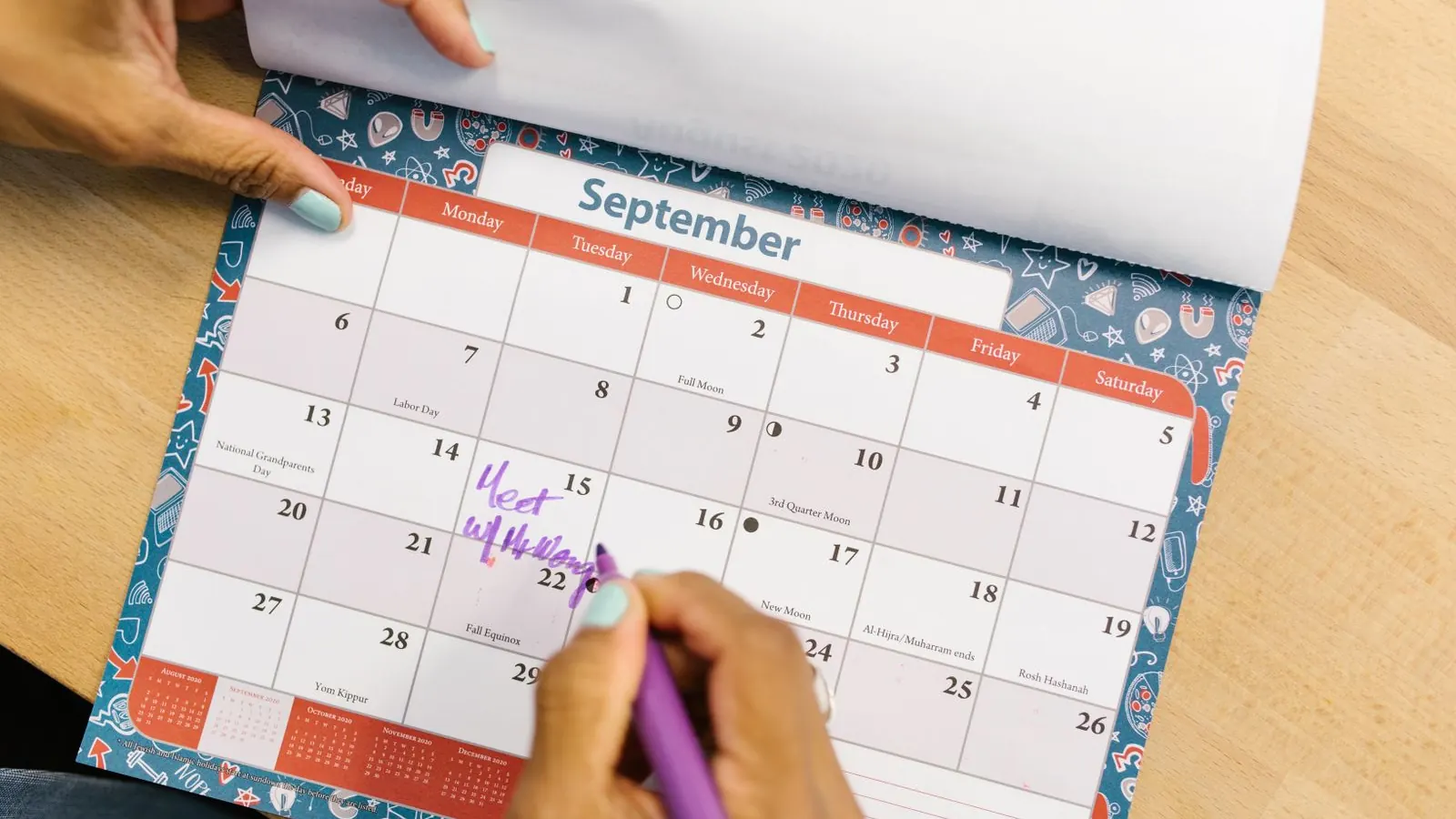 Hand marking a date on a September desk calendar with a purple pen