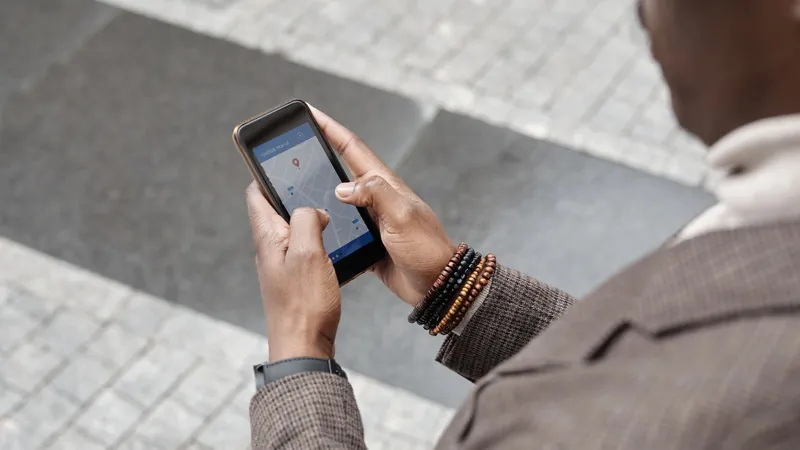 Hands holding a smartphone with a navigation app open on a city street