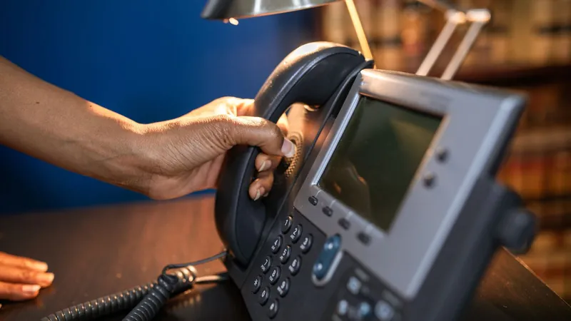 Hand picking up the handset of an office desk phone