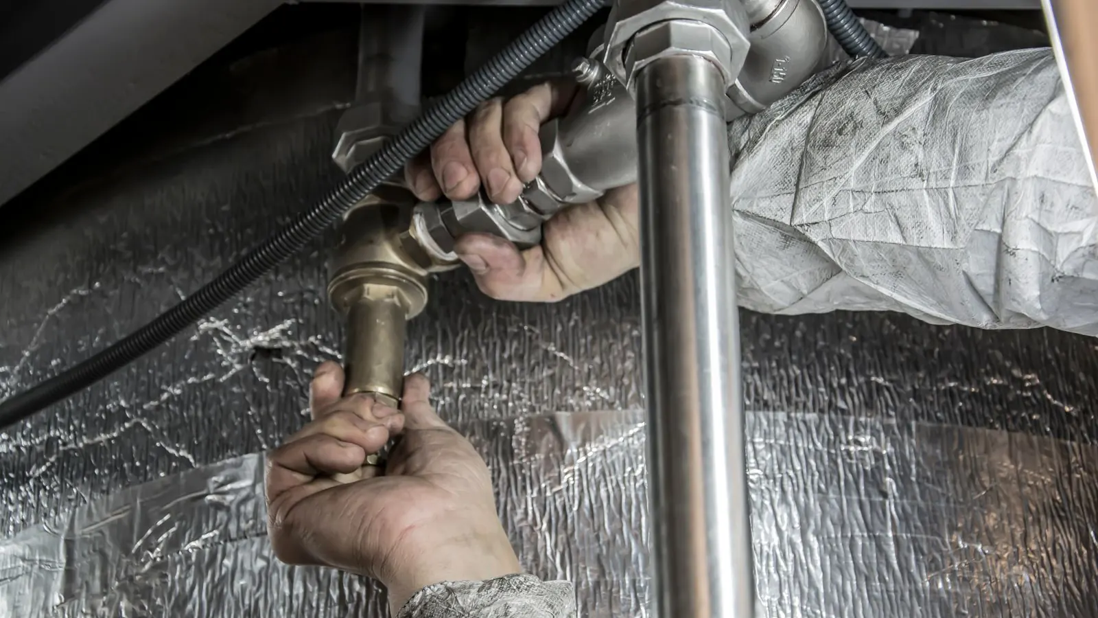 Plumber’s hands fitting a steel pipe during an installation