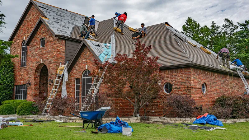 Roofers working on the roof of a brick home in Texas