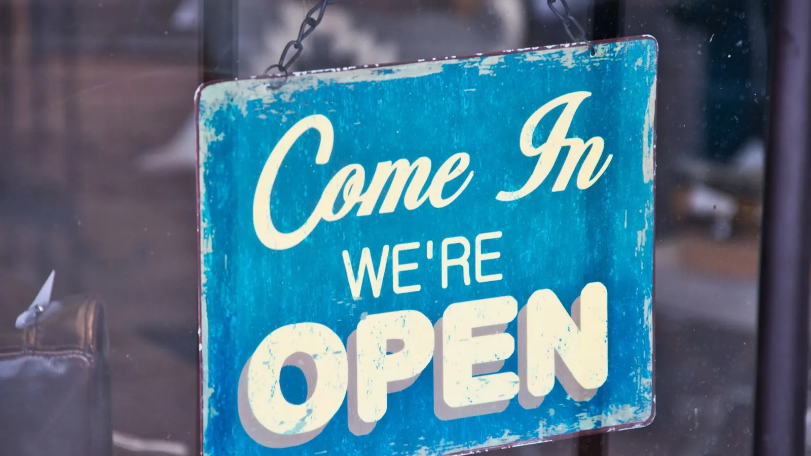 Blue sign reading Come in, we're open hanging on a shop door