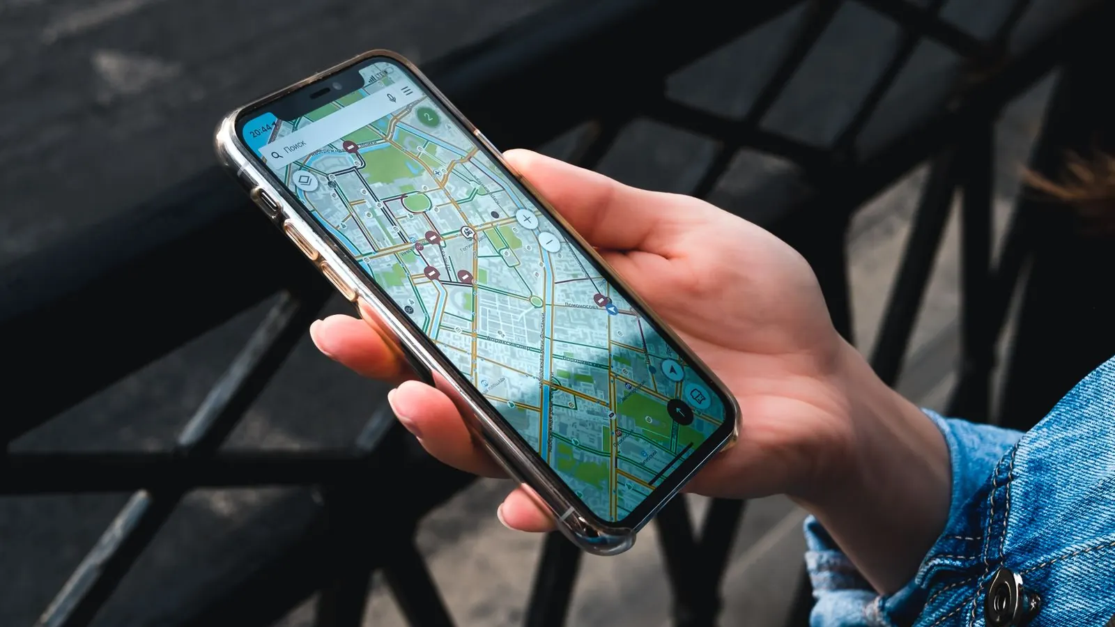 Hand holding a smartphone with a map app open outdoors