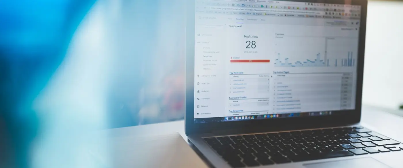 A laptop showing a Google Analytics real-time dashboard with visitor and traffic charts