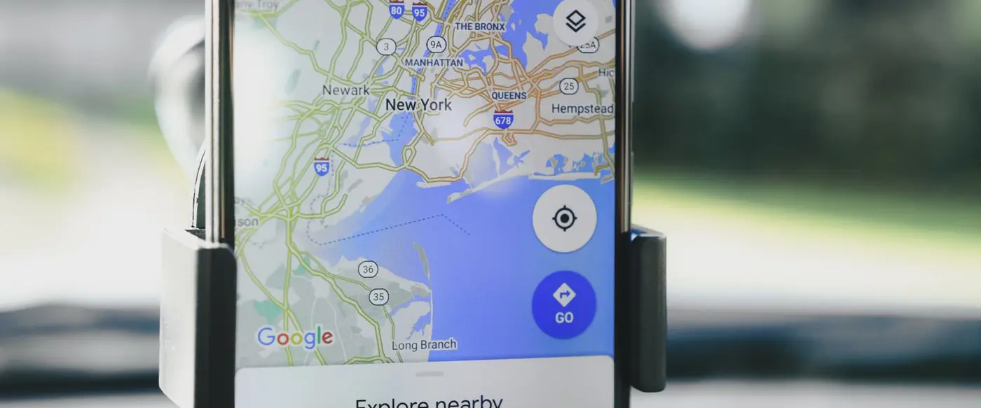 Google Maps open on a phone mounted in a car, showing a city map and nearby places