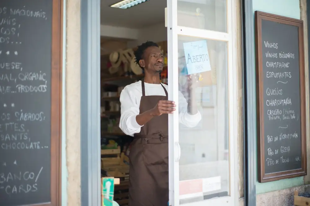 A small business owner in an apron opening the door of his shop for the day