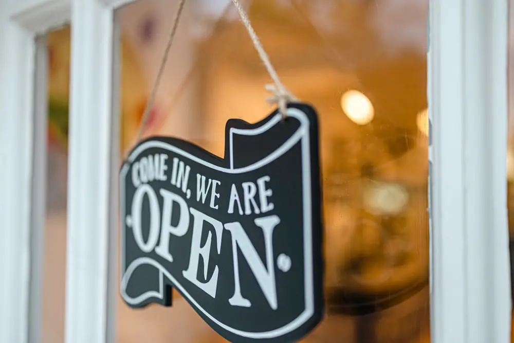 An open sign hanging in the glass door of a local business