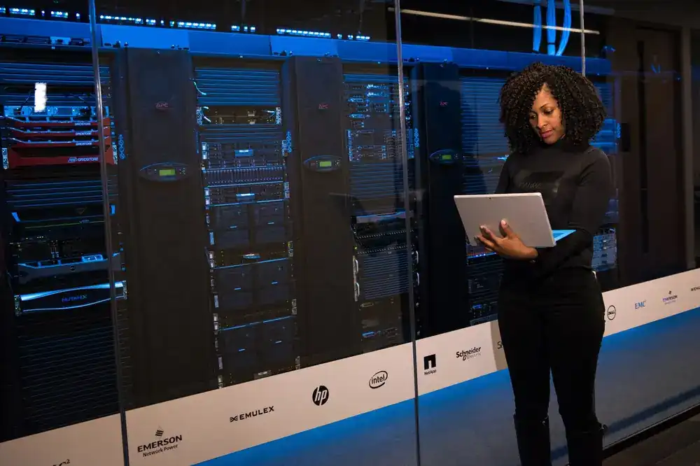An engineer working on a laptop beside server racks in a data centre