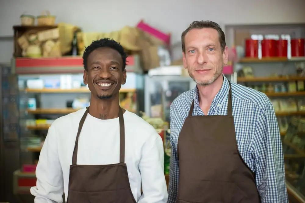 Two small business owners in aprons standing in their shop