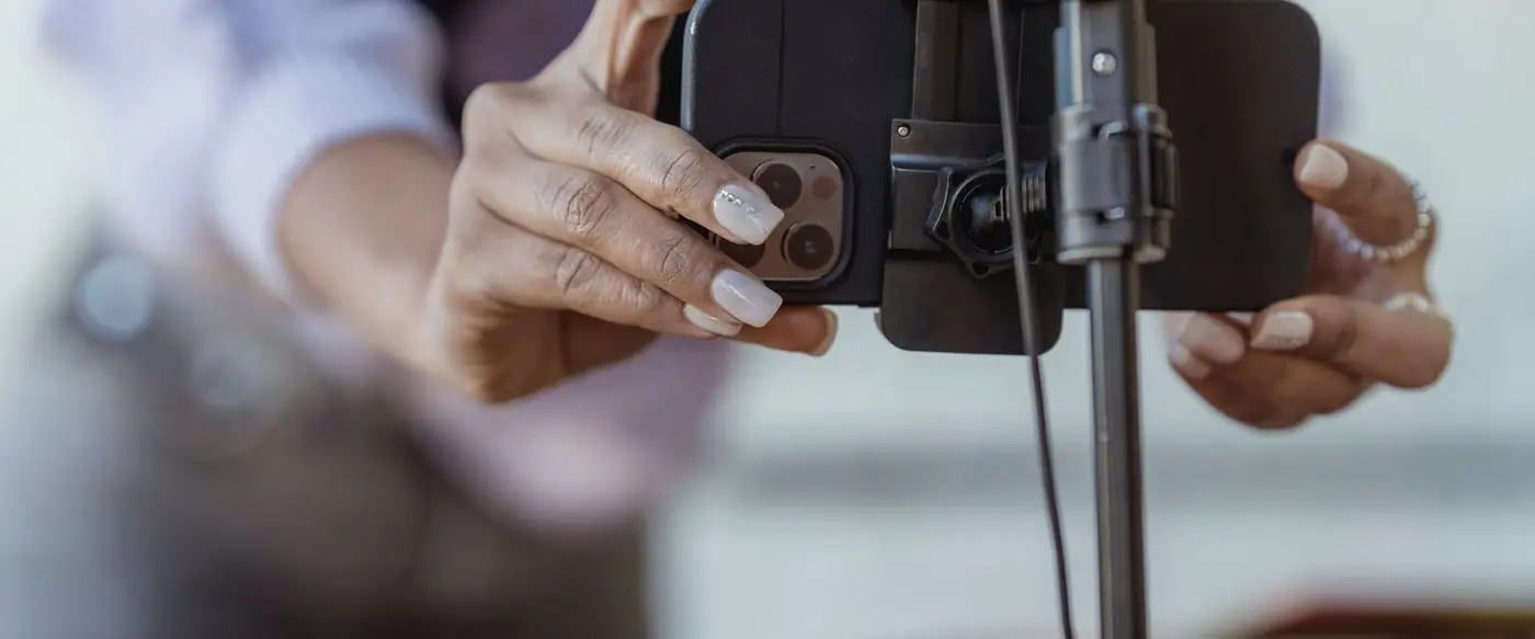 Hands mounting a smartphone onto a tripod to record a video