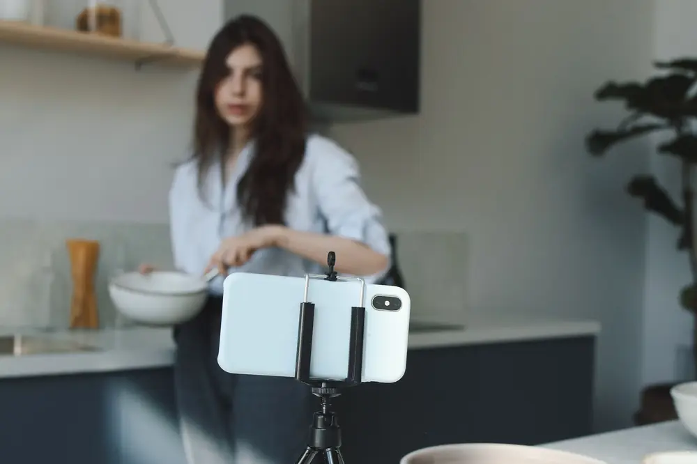 A phone on a tripod recording a person working in a kitchen