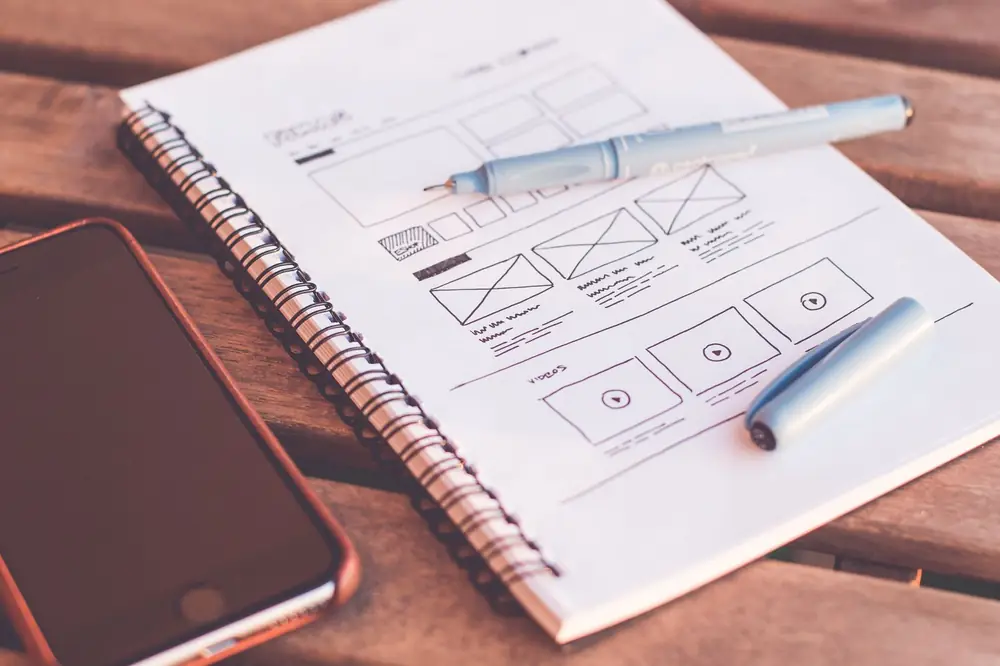 A wireframe sketch of a web page layout in a notebook beside a phone