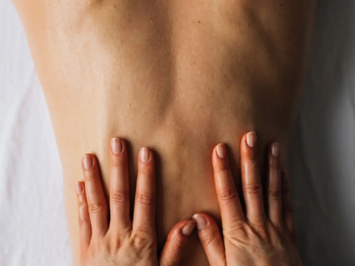 A practitioner's hands applying pressure to a patient's lower back