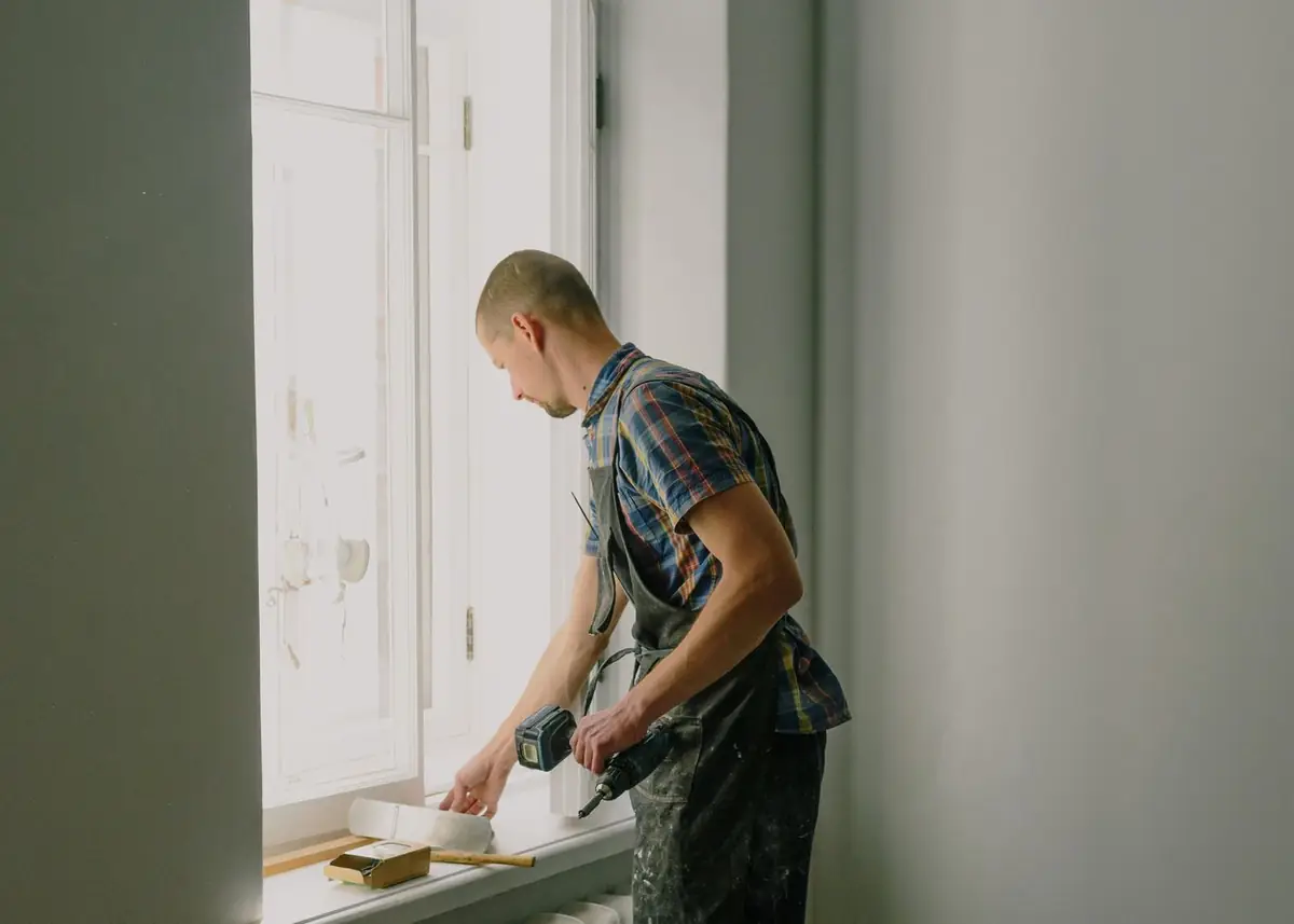 A painter working carefully around a window frame