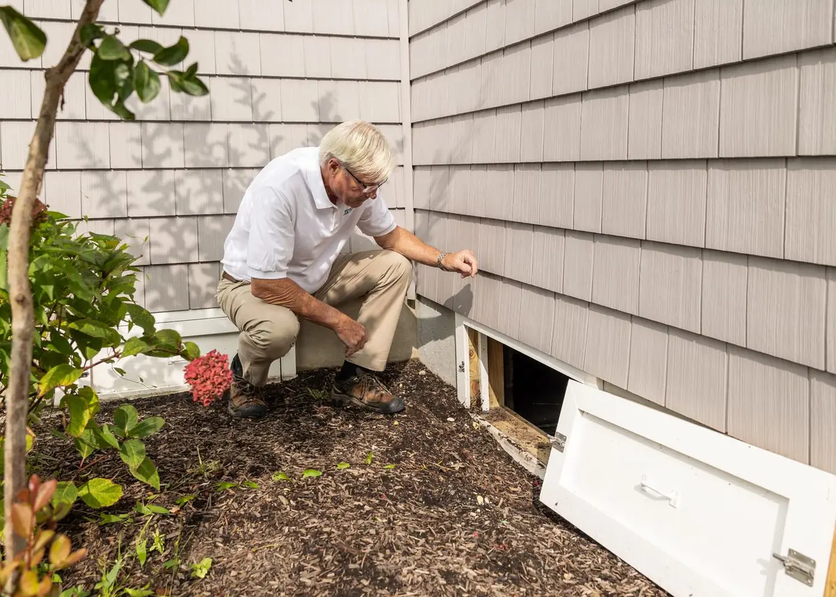 A Sentry technician inspecting the foundation line of a house