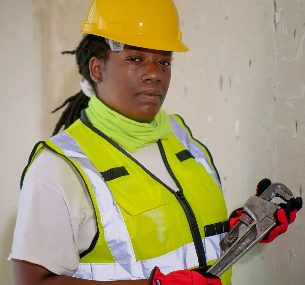 A licensed plumber in high-visibility gear with tools on site