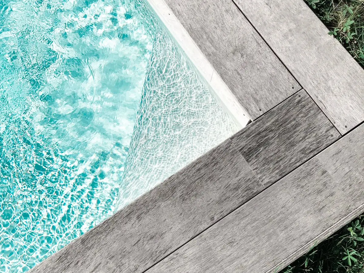 Sunlit turquoise water meeting a timber deck