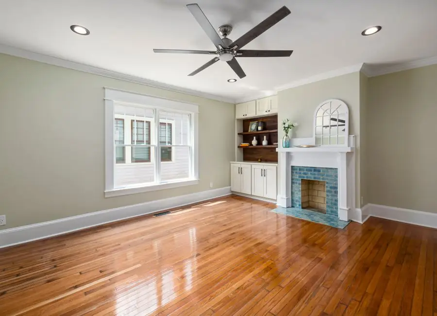 A renovated living room with a restored fireplace and hardwood floors