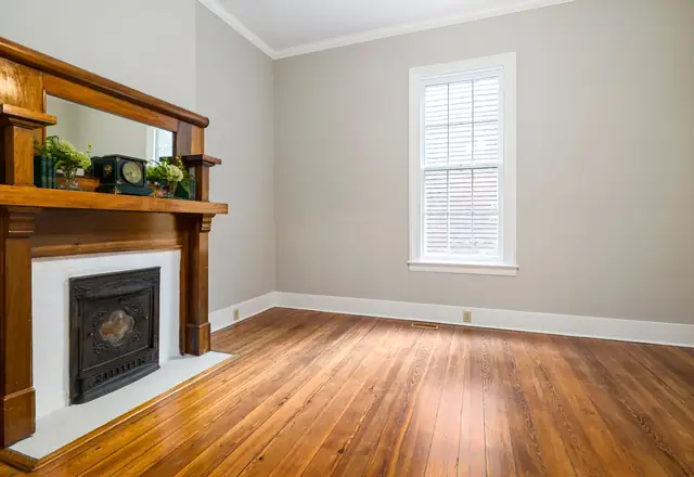 A finished living room with a restored fireplace and hardwood floors, from the property investment website template.