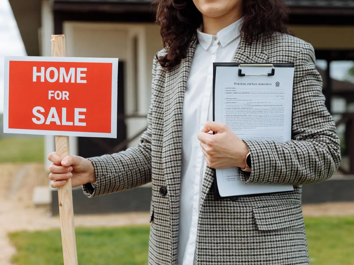 An agent holding a home for sale sign